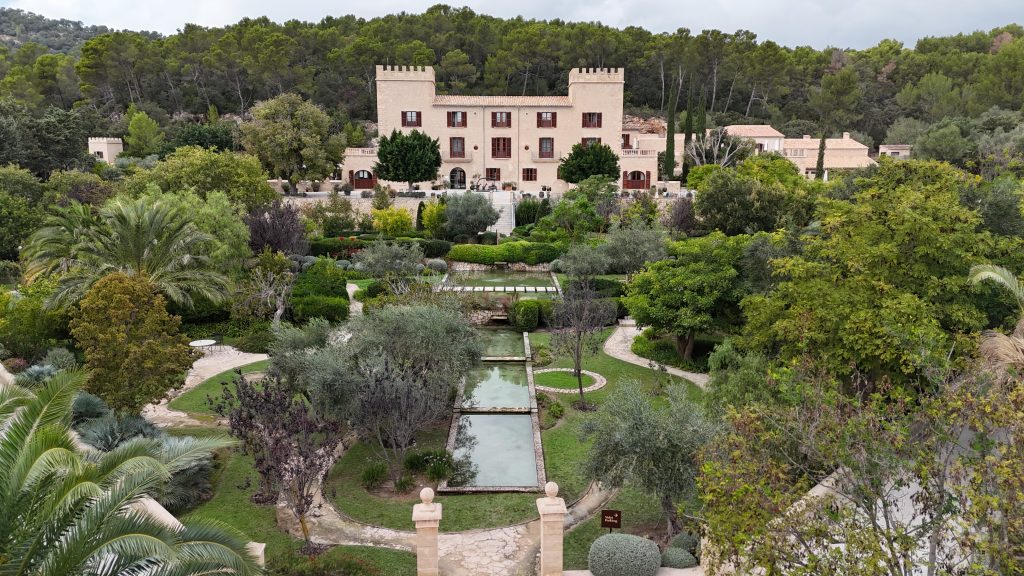 Außenansicht des Castell Son Claret mit Zypressen und Steinmauern
