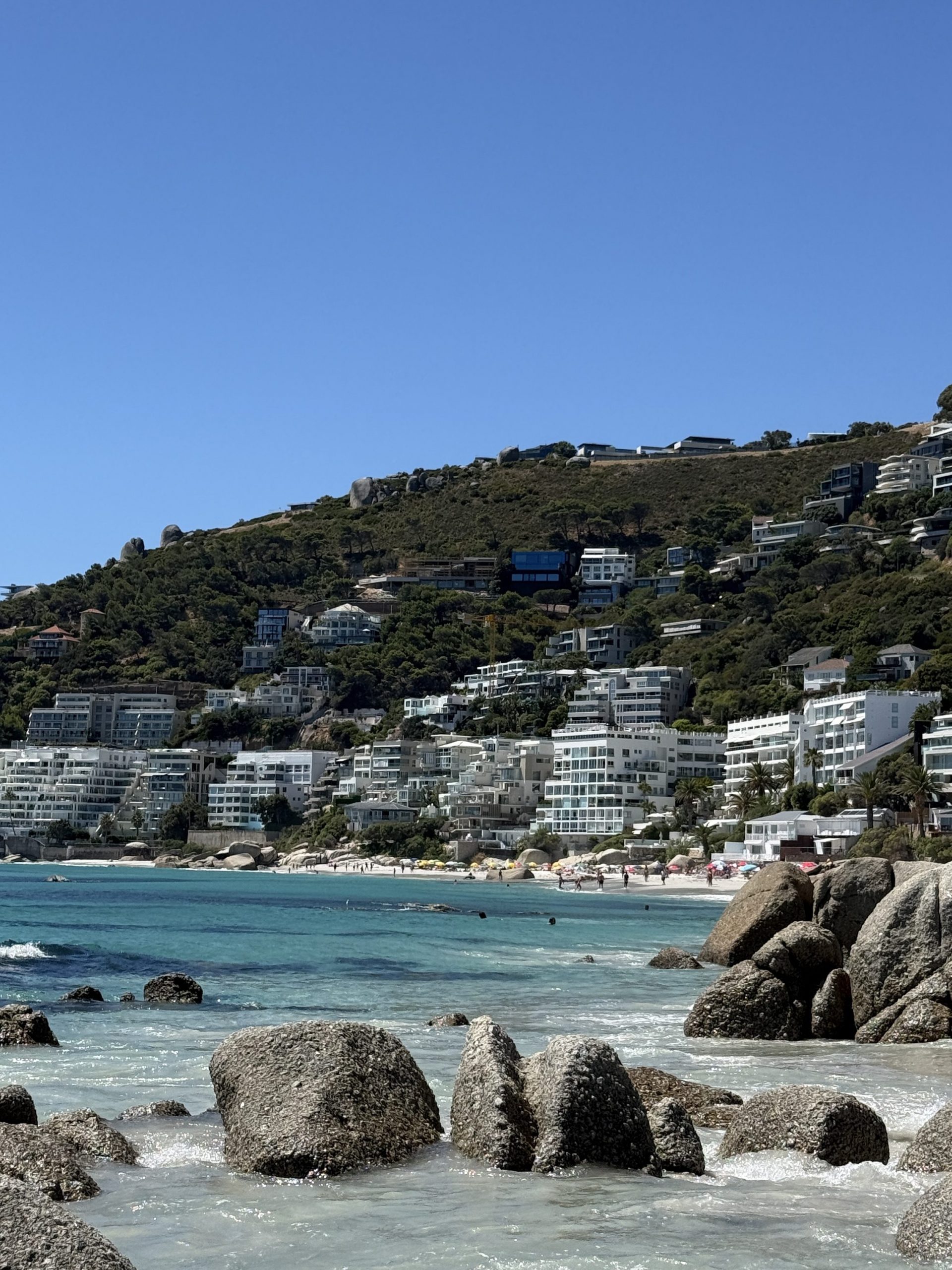 Clifton Beach Promenade in Kapstadt mit einer Häuserfront und einem Berg im Hintergrund